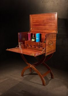 an old fashioned wooden desk with some bottles and glasses on it's trays