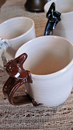 two mugs with brown liquid in them sitting on a table