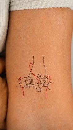 a woman's lower back tattoo with two hands holding each other in red ink