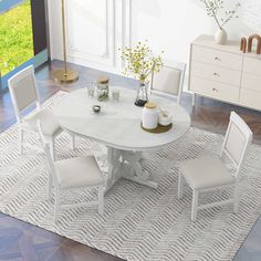 a white dining table with four chairs and a vase filled with flowers on top of it