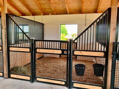 the inside of a horse stable with metal gates and hay in buckets on the floor