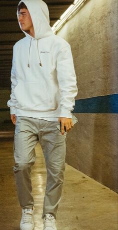 a man in white hoodie and grey sweatpants standing next to an escalator