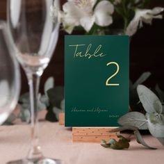 a table number sitting on top of a wooden stand next to a glass filled with water