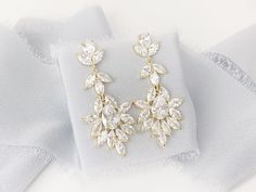 a pair of earrings sitting on top of a white cloth