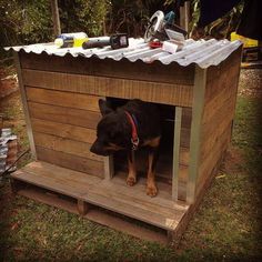 a dog house with a roof made out of pallet boards and wooden planks