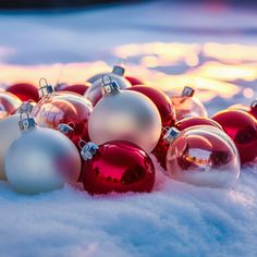 red and white christmas ornaments laying in the snow on top of some snow covered ground