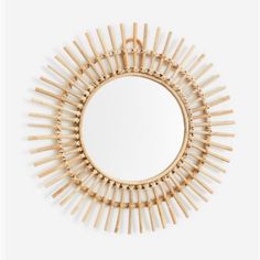 a round mirror that is made out of bamboo sticks and has been placed on the wall