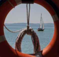 a sailboat in the ocean seen through an orange life preserver