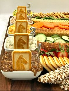 a wooden table topped with lots of different types of sandwiches and dips on top of each other