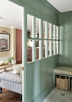 a room with green painted walls and a bench in the corner next to a window