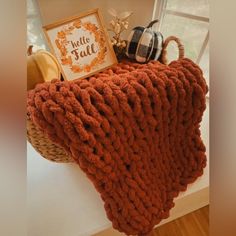 a knitted blanket sitting on top of a window sill next to pumpkins