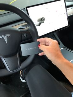 a person holding a card in their hand while sitting in a car with the steering wheel up