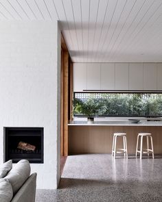 a living room filled with furniture and a fire place in front of a kitchen counter