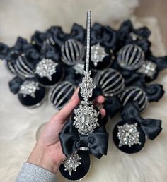 a hand holding a black bow tie and some brooches with bows on them