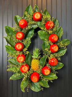 a wreath with tomatoes, pineapples and other fruits on it is hanging on a door