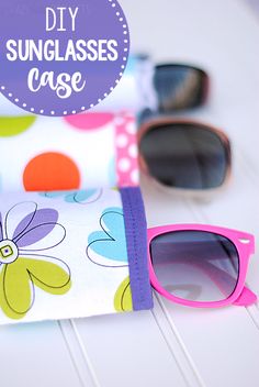 sunglasses case sitting on top of a white table next to two pairs of pink and purple glasses