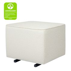 a white ottoman with black legs and a green label on the backgrouding