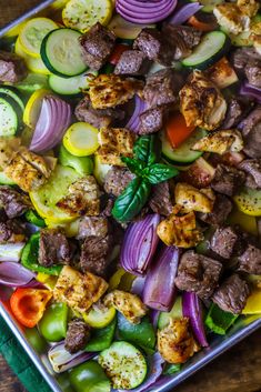 a tray filled with meat and vegetables on top of a wooden table