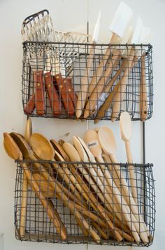 two metal baskets filled with wooden spoons and utensils