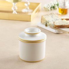 a white canister sitting on top of a table next to bread and wine glasses