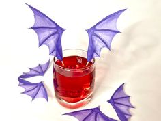 a glass filled with red liquid surrounded by purple bats