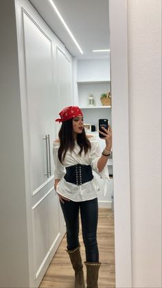 a woman taking a selfie while wearing pirate costume and boots with her phone up to her ear