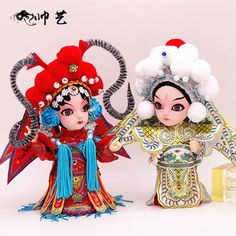 two figurines are standing next to each other on a white surface with chinese writing