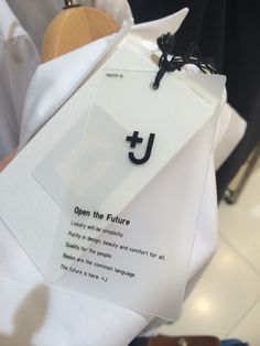 a person holding up a white piece of paper with the letter j on it and an upside down tag attached to it