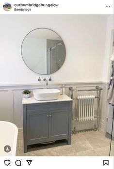 a white sink sitting under a mirror next to a radiator in a bathroom