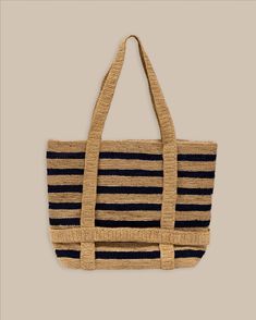 The front view of the Southern Tide Striped Straw Hat Carrier Beach Tote by Southern Tide - Navy Summer Travel Bag Made Of Jute, Lightweight Beachy Straw Bag For Travel, Lightweight Beachy Straw Travel Bag, Adjustable Woven Shoulder Bag For Beach, Eco-friendly Beach Bag For Spring Travel, Spring Eco-friendly Beach Bag For Travel, Eco-friendly Spring Travel Beach Bag, Coastal Beach Bag For Everyday Summer Use, Lightweight Jute Travel Bags