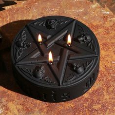 two candles are lit in the shape of a pentagramil on a stone surface