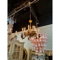 a chandelier hanging from the ceiling with pink ruffles and gold accents