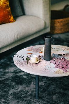 a coffee table with candles on it in front of a couch and pillows behind it