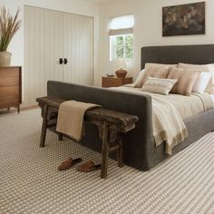 a bedroom with a large bed and wooden foot stools