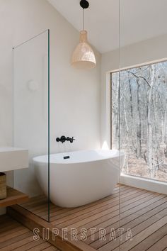 a large white bath tub sitting on top of a wooden floor next to a window