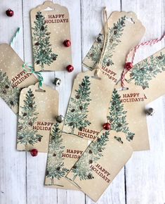 four tags with christmas trees on them are hanging from twine string and decorated with red berries