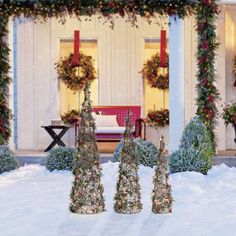 christmas decorations in front of a house with snow on the ground and wreaths all around