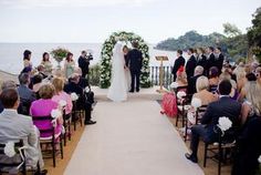 a bride and groom standing at the end of their wedding ceremony with an ocean view