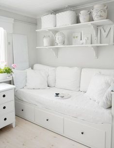 a white couch sitting next to a shelf filled with vases