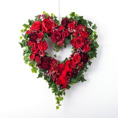 a heart shaped wreath with red roses and greenery