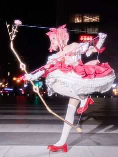 a woman dressed in white and pink is holding a bow while standing on the street