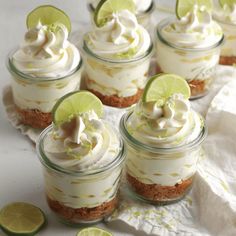 there are many desserts in small glass jars with lime slices on the table next to them