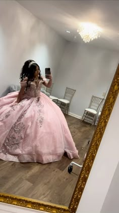 a woman in a pink dress taking a selfie with her cell phone while sitting on the floor