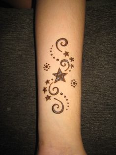 a wrist tattoo with stars and swirls on it