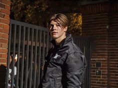 a young man standing in front of a gate with a lit candle on the ground