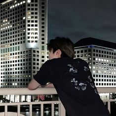 a man standing on top of a balcony next to a tall building at night time