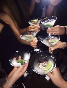 a group of people holding wine glasses with food in them