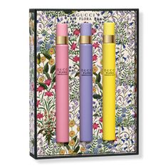 three different colored tubes in front of a floral wallpapered box with flowers on it