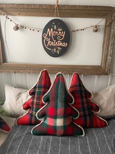 a christmas tree pillow sitting on top of a bed in front of a sign that says merry christmas