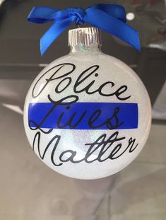 a glass ornament with the words police lines on it and a blue ribbon